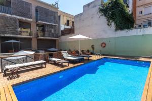 a swimming pool with benches and umbrellas next to a building at Apartment Barcelona Rentals - Gracia Pool Apartments Center in Barcelona
