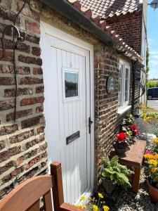 eine weiße Tür an der Seite eines Backsteingebäudes in der Unterkunft Yarm cottages Haystack in Kirk Leavington