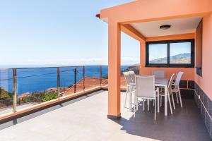 einen Balkon mit einem Tisch und Stühlen sowie Meerblick in der Unterkunft Casa Por Do Sol ll in Arco da Calheta