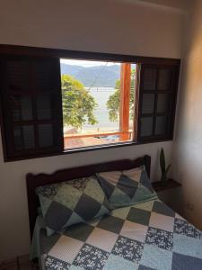 a bedroom with a window and a bed with a view at Casa amarela in Cambaquara
