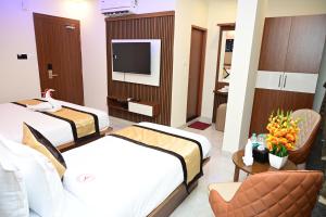 a hotel room with two beds and a television at Aanvi Suites RR nagar in Bangalore