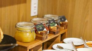 a table with jars of honey and plates of food at Hotel Greenville by Slim Hotéis in Primavera do Leste