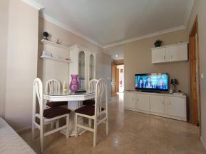 comedor con mesa blanca y TV en Playa Rincón de la Victoria en Plaza San Francisco, en Rincón de la Victoria