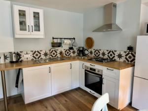 a kitchen with white cabinets and a wooden counter top at L'atelier du Vannier in Fayl-Billot
