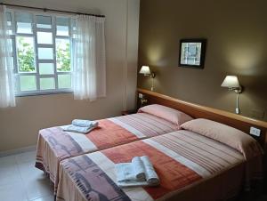ein Schlafzimmer mit einem Bett, auf dem zwei Handtücher liegen in der Unterkunft Hostal León II in Porto do Son