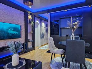 a dining room with a table and chairs and a tv at POSEJDON DELUXe 3 in Vrnjačka Banja