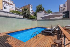 a swimming pool on a wooden deck with an umbrella at My Space Emirates - Bright Apartment in Gracia with shared Pool in Barcelona