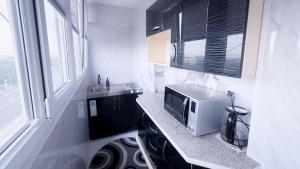 Una pequeña cocina con microondas y fregadero. en Panoramic apartment on Hamid Alimjan square, en Salor Bekati
