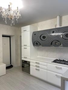 a kitchen with white cabinets and a chandelier at Квартира в историческом центре Одессы in Odesa +15 photos