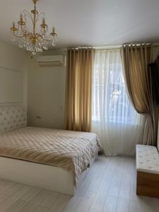a bedroom with a bed and a chandelier and a window at Квартира в историческом центре Одессы in Odesa