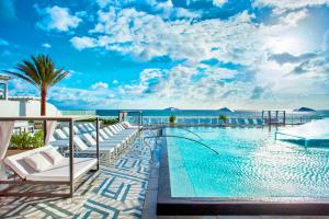 a swimming pool with chairs and the ocean in the background at Exclusive Beachfront Condo at W Fort Lauderdale in Fort Lauderdale