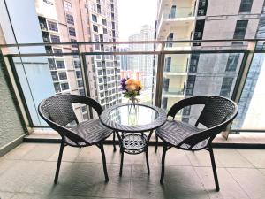 Summer Luxury Suites KlCC by ATIQ في كوالالمبور: طاولة زجاجية مع كرسيين ومزهرية زهور على شرفة