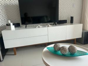 a white cabinet with a tv and two balls on a table at Oka Beach Residence Muro Alto in Cupe