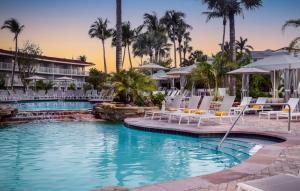 a pool at a resort with chairs and umbrellas at La Playa Beach & Golf Resort, a Noble House Resort in Naples