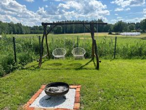 a grill in a field with two chairs in the grass at Domek pod jesionami in Ruciane-Nida +2 photos