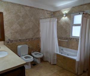 a bathroom with a toilet and a tub and a sink at Casa de Campo Petit Lodge in Estancia Grande