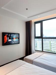 a hotel room with two beds and a large window at Sapphire House Hạ Long in Ha Long