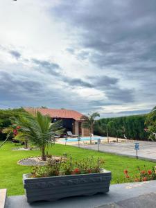 a park with a building with a palm tree and flowers at Chalé Caju Beach - Barra Grande Piauí in Barra Grande