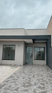 a large building with glass doors and a stone driveway at Furnished house in Fazenda Rio Grande