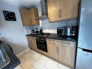 a kitchen with wooden cabinets and a stove top oven at Wessex Stays - Spacious 1 Bedroom Property in Willaston