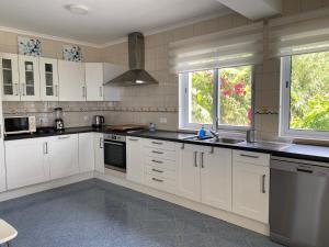 a large kitchen with white cabinets and windows at A casa da Xã in Almagreira