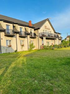a large building with a lawn in front of it at Pokoje gościnne Becia in Łeba