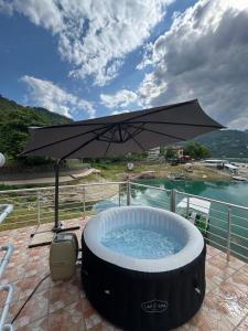 a hot tub with an umbrella on a patio at Casa Del Lago in Jablanica +11 photos