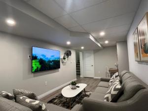 a living room with a couch and a tv on a wall at The Place in Winnipeg