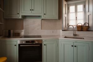 a kitchen with white cabinets and a sink and a stove at MAZAS House in Kámbos
