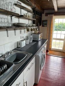 a kitchen with a sink and a washing machine at Yarm cottages the rafters in Kirk Leavington +8 photos