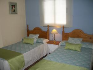 sypialnia z 2 łóżkami, lampką i oknem w obiekcie Hostal Rural Gloria w mieście Graena