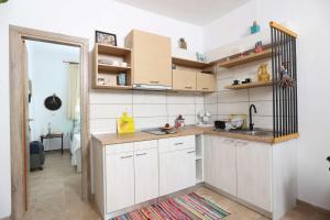 a kitchen with white cabinets and wooden shelves at Η Μουριά, The Mouria House in Pefkochori +11 photos
