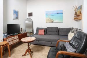 a living room with a couch and a tv at Η Μουριά, The Mouria House in Pefkochori
