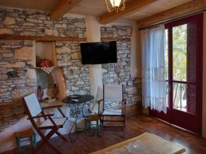 a living room with a stone wall with chairs and a tv at Casa Sofia in Mytilinioí