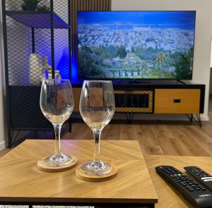 two wine glasses sitting on a table in front of a television at Eden apartment in Haifa