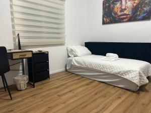 a bedroom with a bed and a desk and a painting at Eden apartment in Haifa