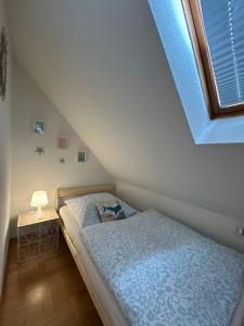 a bedroom with a bed with a blue comforter and a window at Ferienhaus Lines to Huus bei Heiligenhafen und Großenbrode in Heiligenhafen