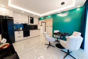 een keuken met een tafel en witte stoelen en een groene muur bij Уют in Bŭnzareto