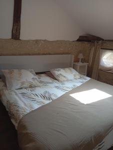 a bed with white sheets and pillows in a bedroom at La chaise in Saint-Aquilin