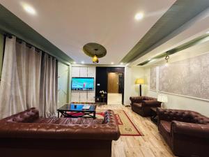 a living room with leather couches and a television at Galiyaat View By AlFateh Hotel in Murree