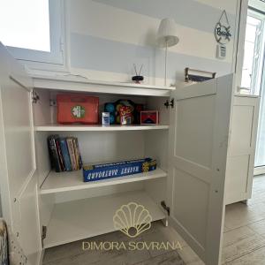 a white book shelf in a room with books at Villa Alessia - La Conchiglia in San Pietro in Bevagna