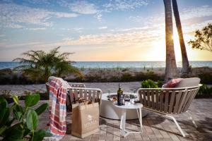 a patio with a table and chairs and the ocean at La Playa Beach & Golf Resort, a Noble House Resort in Naples