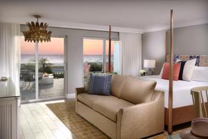 a bedroom with a bed and a couch with a view of the ocean at La Playa Beach & Golf Resort, a Noble House Resort in Naples