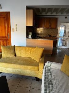 a yellow couch in a living room with a kitchen at Syrine's house in Monastir