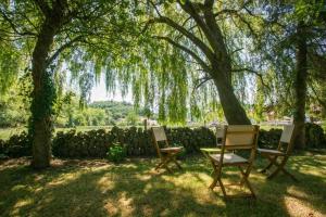 two chairs and a table under a tree at Posada La Fuentona de Ruente in Ruente