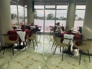 ein Restaurant mit Tischen und Stühlen in einem Raum mit Fenstern in der Unterkunft Gillu Hotel in Nazrēt