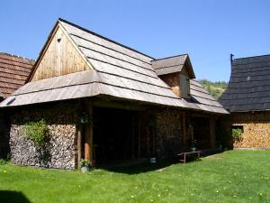eine alte Scheune mit einem Dach auf einem grünen Feld in der Unterkunft Retro Cottage Osturna in Osturňa