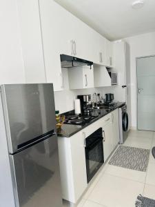 a kitchen with white cabinets and a stainless steel refrigerator at Reamo Suites in Gaborone