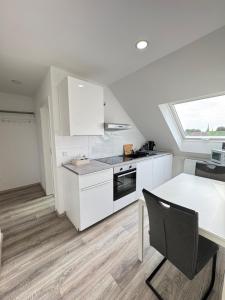 a kitchen with white cabinets and a table and a window at Am Zollverein Ferienwohnung Apartment Essen - Free Parking - WiFi - Kitchen in Essen