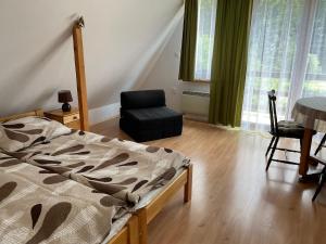 a bedroom with a bed and a chair and window at Domek u Pawła in Piwniczna